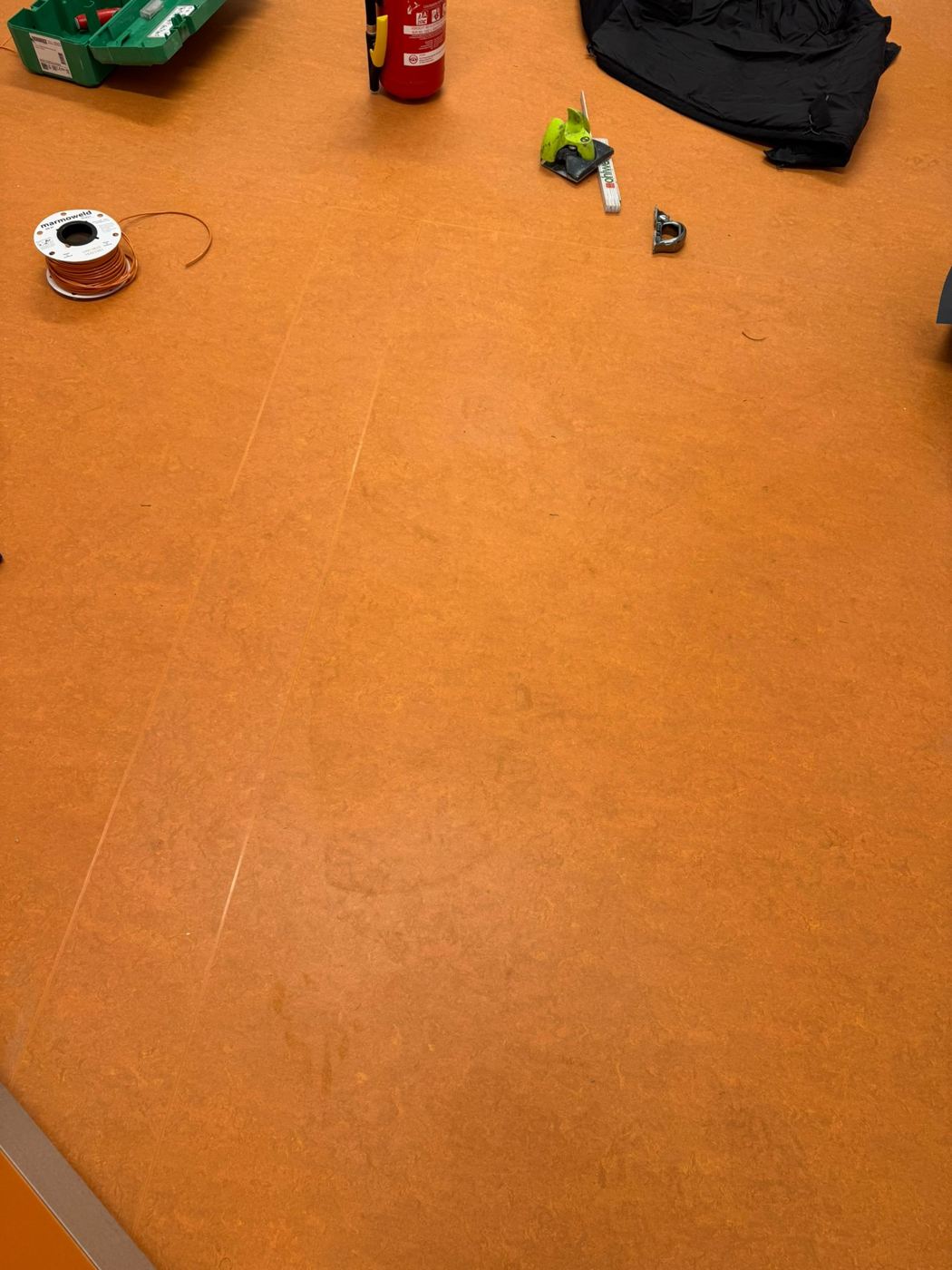 Linoleum orange mit Marmoweld-Schmelzdraht und Werkzeug beim thermischen Verschweissen der Naehte