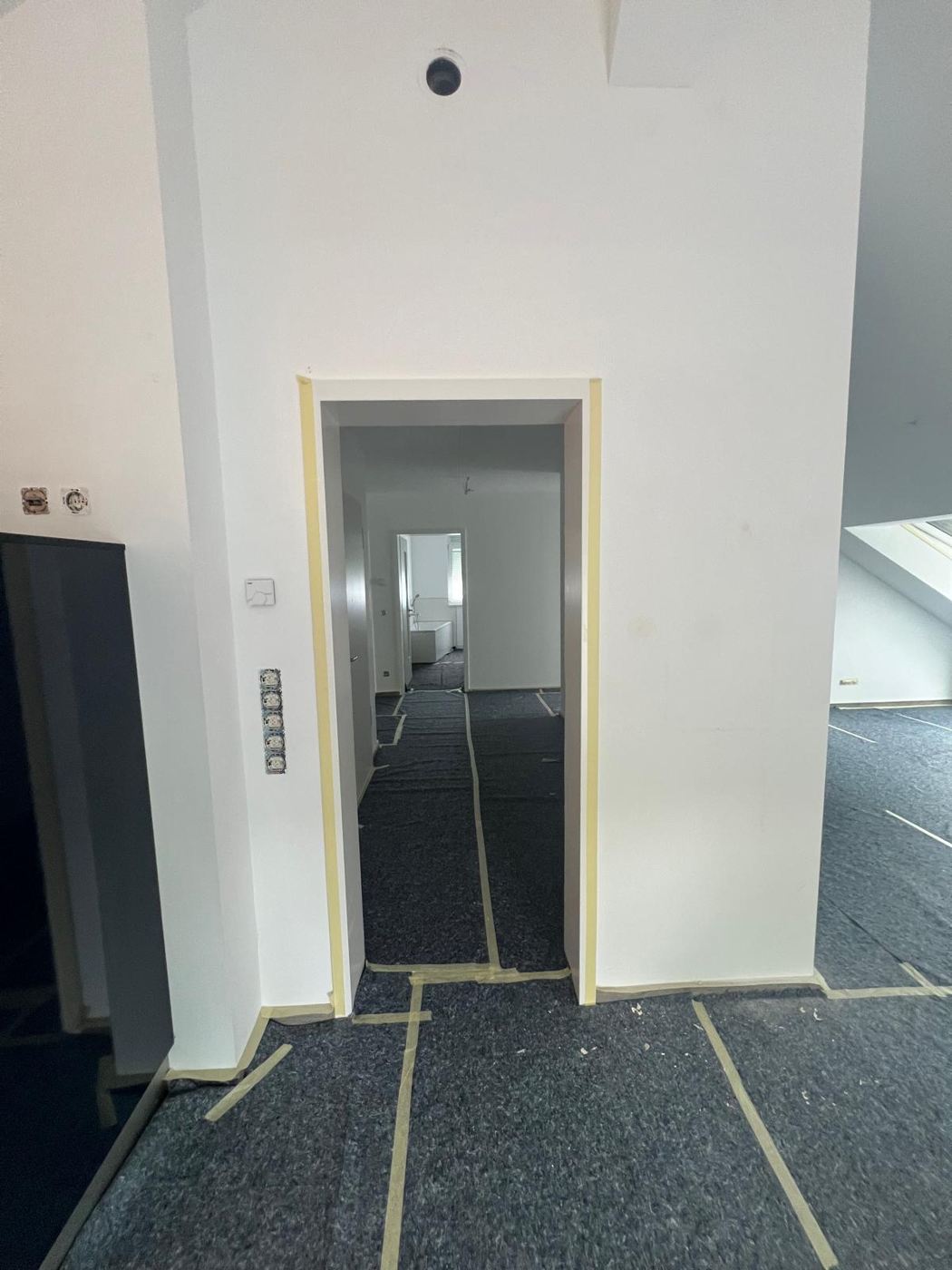 Frisch gestrichenes Dachgeschoss-Zimmer mit Schutzvlies auf dem Boden